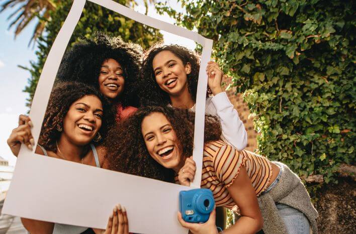 Group of girls smiling in an empty picture frame | image accompanies a blog post by Truth Tree on the use of instagram now that it's indexed by Google | Truth Tree provides digital marketing strategies and solutions for private schools